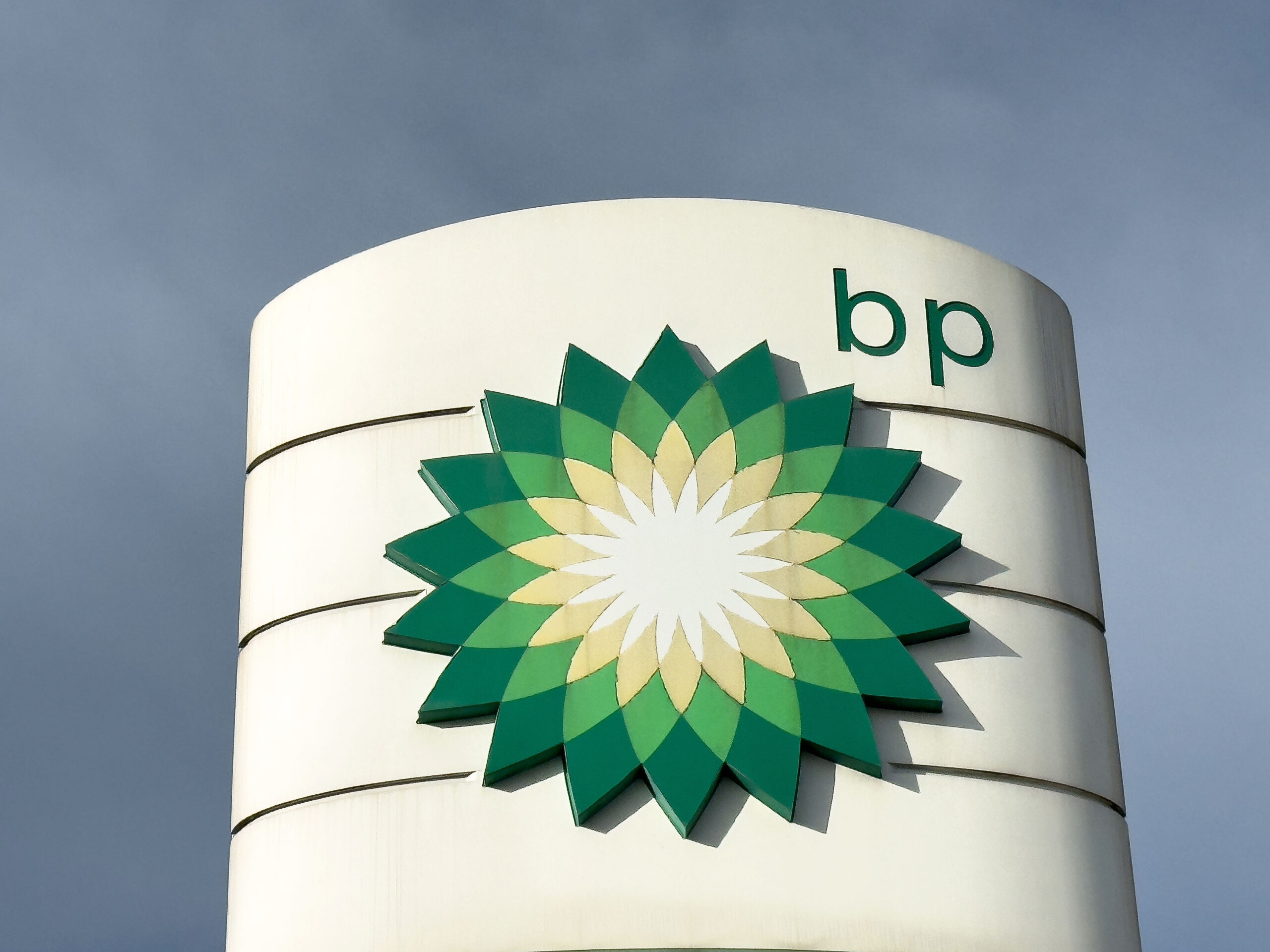 Bp logo on modern architectural structure against cloudy sky.