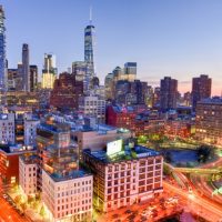The skyline of downtown Manhattan, New York at sunset with trails of traffic in the street.