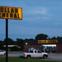September 20, 2025, Sallisaw, Oklahoma. Dollar General store at twilight. Exterior of store and sign are lighted at dawn, vehicles in the parking lot, lights on inside. Propane tanks available outdoors. The rretail store chain is common in the region.