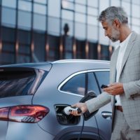 A man holding power supply cable at electric vehicle charging station, closeup